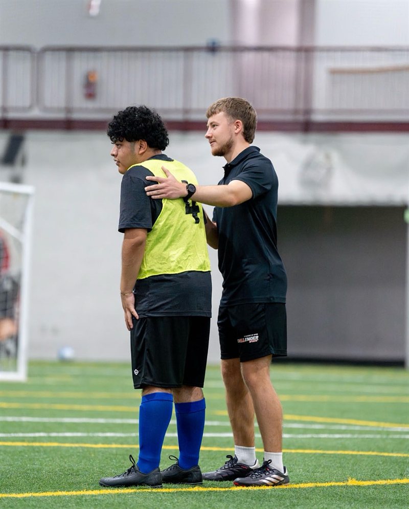 Lucas Sutherland coaching a player on the pitch